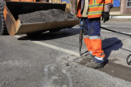 团队道路维修工人在施期间用一部手推机将旧沥青从公路上的旧沥青清除出来在道路建设过程中一名工人用台充气大锤清除了一块沥青男人行业出去高清图片素材