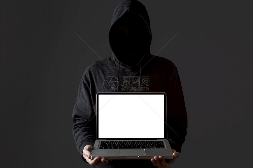 盗窃身份匿名的持有膝上型计算机的男黑客高清晰度照片前视图持有膝上型计算机的男黑客高品质照片图片