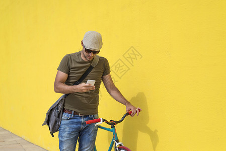 冒险街道技术特伦迪男人坐在固定自行车上时在户外使用智能手机背景图片