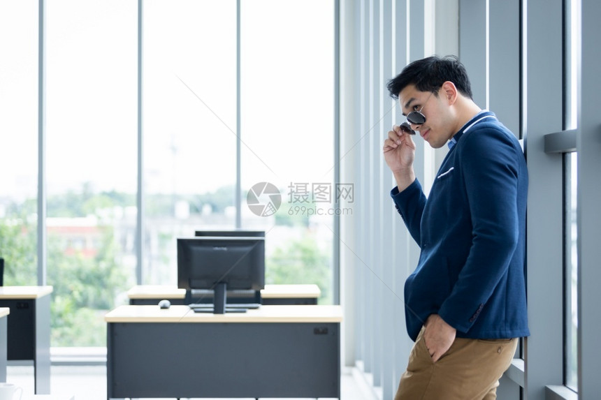 身着蓝夹克和衬衫的人穿着商业西装在办公室背景中触摸眼镜的玻璃窗上BlueT恤衫穿着男子的衣服看公司成功图片
