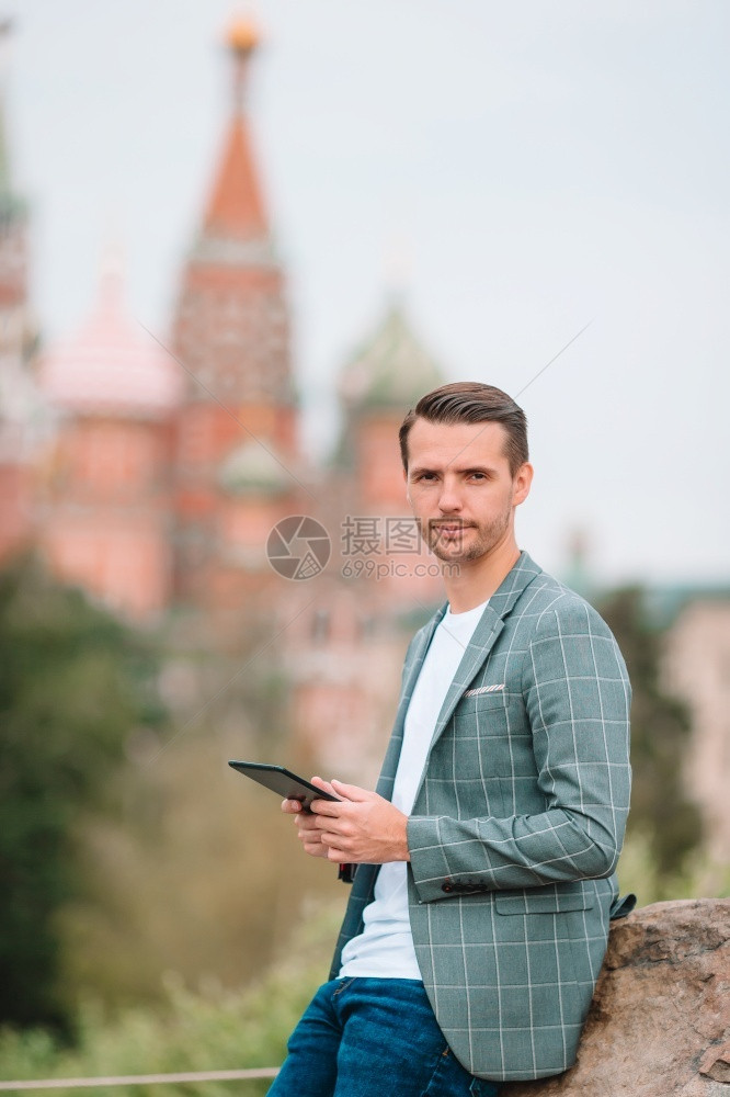 镇在圣巴西尔斯教堂和克里姆林宫肖像背景上有电话户外的青年男子莫斯科快乐城市青年男子欢乐在欧洲市商人的克里姆林宫肖像游客图片