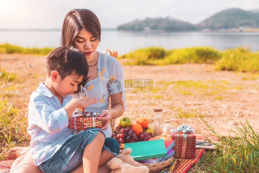 时间户外喜悦美丽的亚洲母亲和儿子做野餐及生日派对在湖边山上草地原的生日惊喜礼物箱开放盒人们的生活方式与幸福家庭生活概念节假日度图片