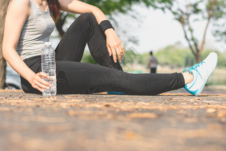 自然一名健身妇女坐在户外公园健康运动概念的街上喝着一瓶水在街上坐着道和平摆姿势高清图片素材