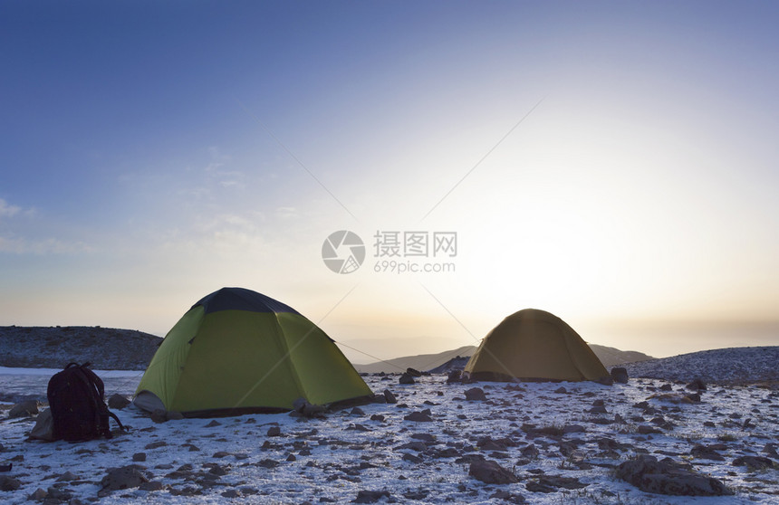游客的背包和帐篷位于山顶与清蓝天空相对日落的晨晒在山顶游客的背包和帐篷在山顶以及游客的背包和帐篷设在山顶蓝色的无雪爬坡道图片