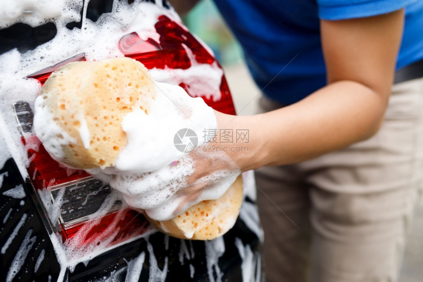 肥皂水保持蓝色的有手黄海绵和泡沫清洗窗的工人男子手持黄海绵和泡沫洗车用擦玻璃窗户图片