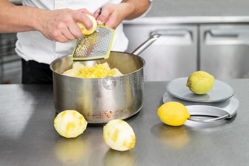 行动白种人Pastrychefrsquos手在商业厨房中磨碎柠檬厨师在刨丝器上磨碎酸橙以获得烹饪制作糕点健康食品天然补的热情特写图片