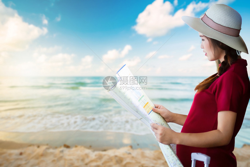身着红色礼服携带行李的亚洲妇女怀孕看清晨日出时的和沙滩海浪地平线背景霍利旅行概念等图快乐的指导背包客图片