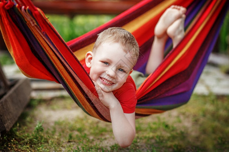 纺织品脚丫子美丽的快乐小男孩在吊床上休息玩得开心积极的情绪颜色背景图片