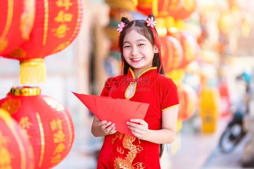 保持身着青山传统红衣装饰的亚裔女孩手握红色信封和灯笼上面写着中文字祝福是新年的分节日钱图片