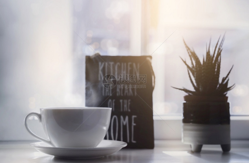 高钥匙轻亮的白茶杯窗边有模糊的仙人掌锅热咖啡杯蒸汽舒适和温暖的清静阳光明亮清晨照到厨房窗户杯子复古的制作图片