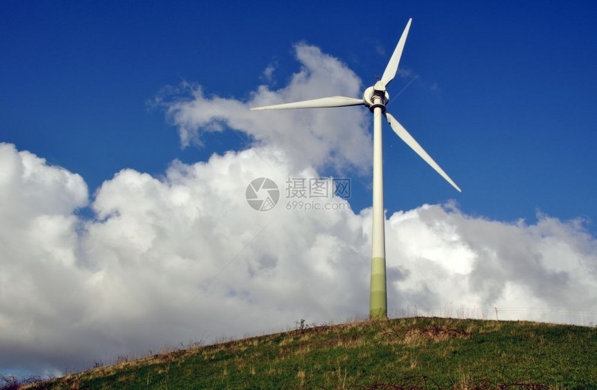 创新绿色山上作为替代能源的风力涡轮机与前面有灌木和栅栏的蓝云天空相对来源正面图片
