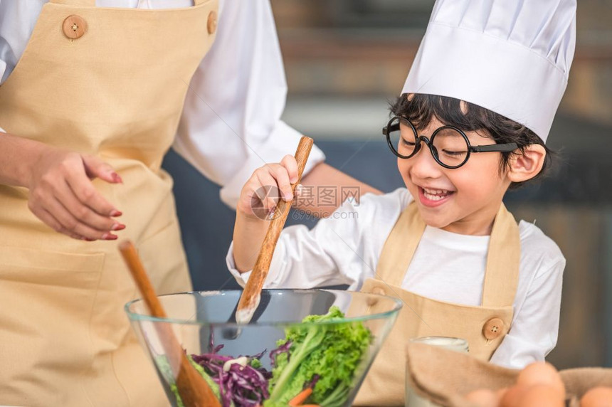 在室内爱做饭的亚洲小可爱男孩在家庭厨房里和妈一起做饭很滑稽人们的生活方式和家庭自制食物原料概念两个泰国人制作了由水生食物沙拉酮可图片