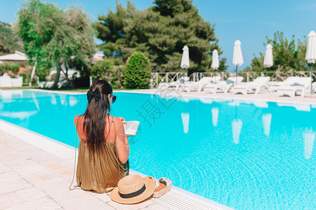 女人在泳池边看书享受游泳的高清图片素材