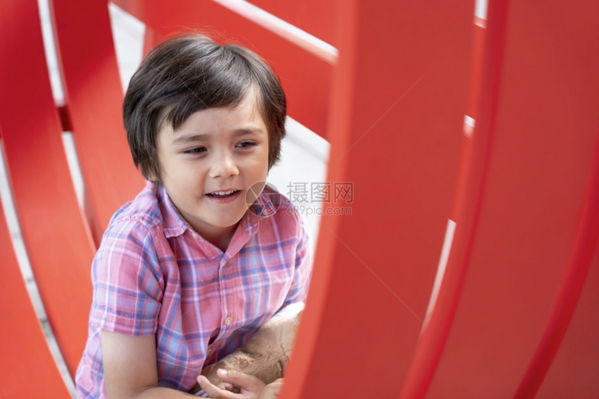 男生坐在红椅子上快乐的孩坐在红椅上健康的孩玩户外金属椅子的健康儿童在春季或暑假的节日里在外面玩乐的年轻男孩积极儿童概念公园英俊的图片