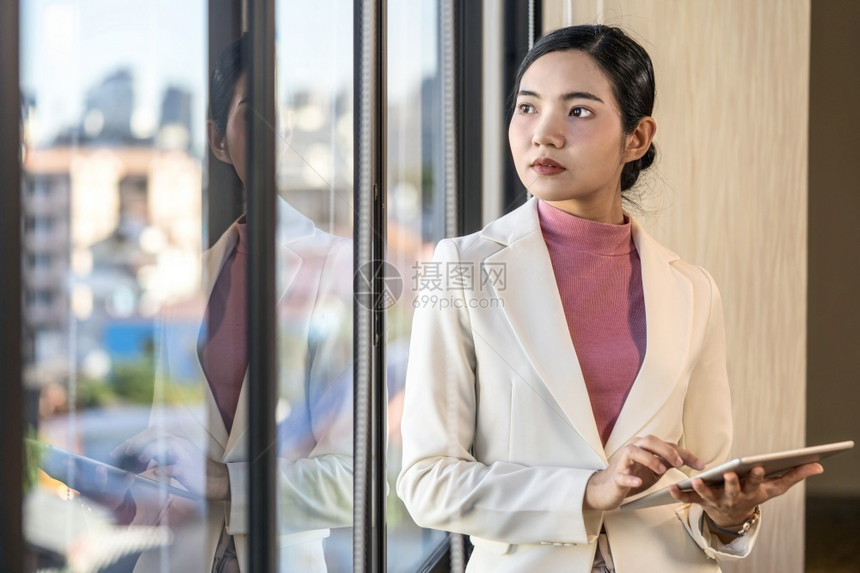 女士成人在玻璃窗商业和生活方式概念之外站立并持有技术平板的亚洲临时穿便衣女亚洲商业妇工作图片