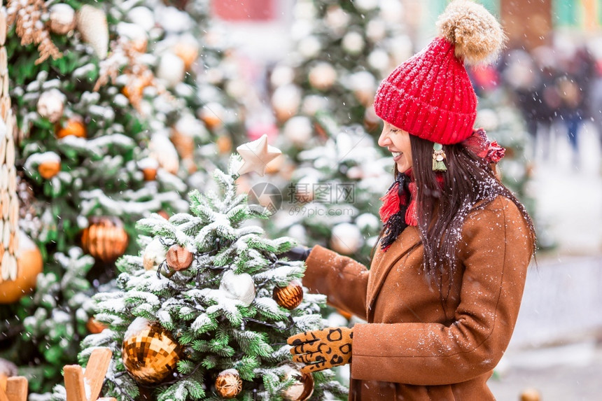 白色的Beautidul身戴红帽子的女人在圣诞节的雪天快乐女孩在雪中的firtree树枝附近新年圣诞老人幸福图片
