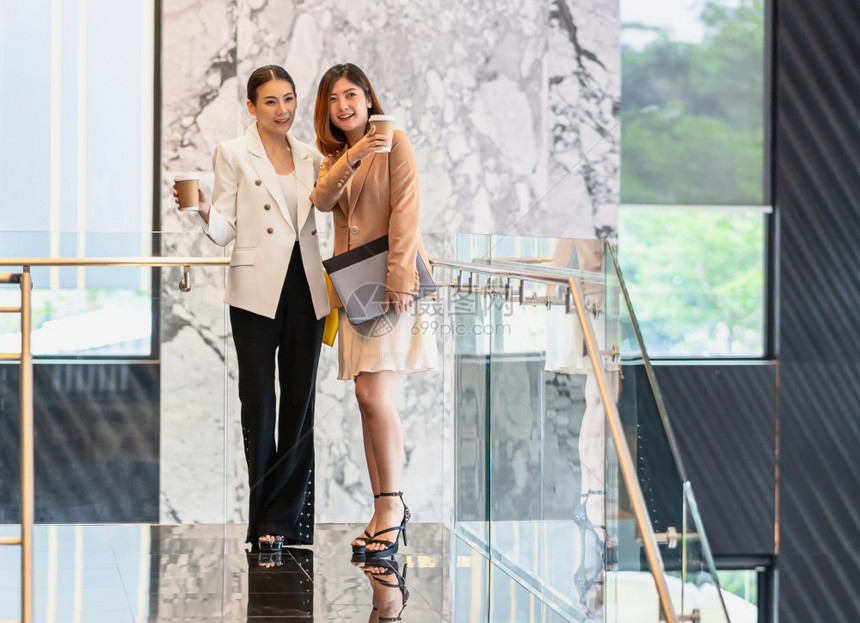 在现代办公室或合用场所的咖啡休息期间两名女亚洲企业家在咖啡休息期间散步和说话咖啡休息下班后放松和谈话商业人的伙伴关系概念妇女成人图片