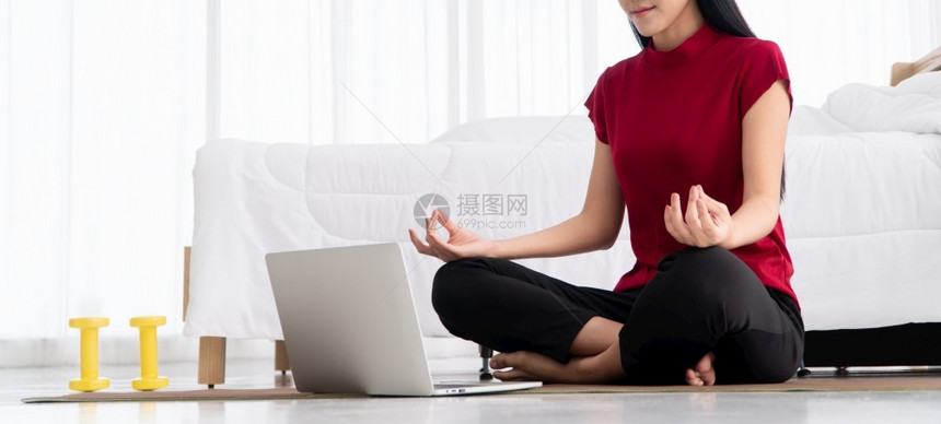 有氧运动健康的亚洲年轻妇女在卧室里进行瑜伽锻炼在家里用笔记本电脑在线学习运动和放松概念技术促进新正常生活方式的创新与放松概念为健图片