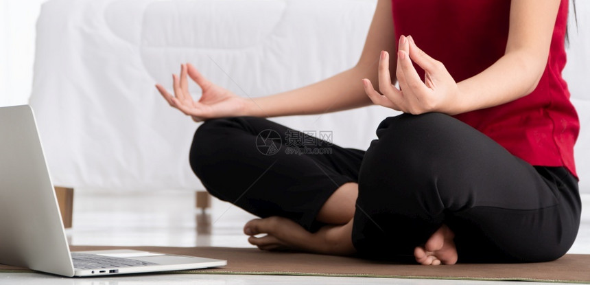 健康的亚洲年轻妇女在卧室里进行瑜伽锻炼在家里用笔记本电脑在线学习运动和放松概念技术促进新正常生活方式的创新与放松概念为健康青年妇图片