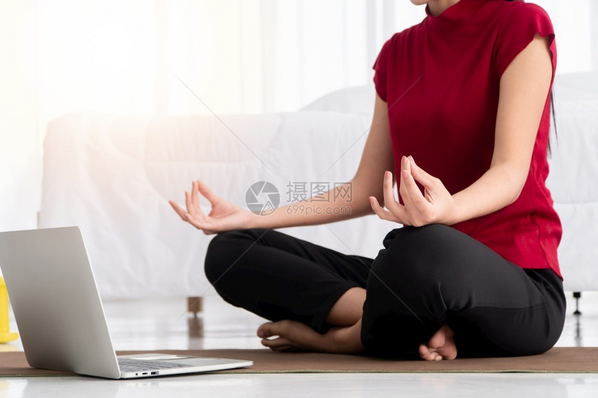 冥想健康的亚洲年轻妇女在卧室里进行瑜伽锻炼在家里用笔记本电脑在线学习运动和放松概念技术促进新正常生活方式的创新与放松概念为健康青图片