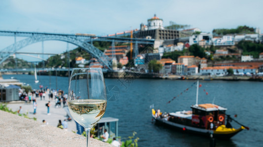 喝白葡萄酒吸引力葡萄牙波尔图杜罗河上俯瞰CaisdaRibeira和PontedeDomLuisI的白葡萄酒杯选择焦点玻璃上桥的反射白葡萄背景