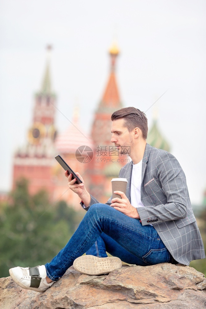 学生游客城市青年男子在莫斯科圣巴西尔教堂背景下用笔记本电脑工作在户外喝咖啡莫斯科快乐城市青年男子在欧洲城市喝咖啡图片