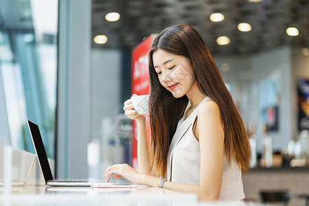 街舞潮店素材现代的共同工作药片亚洲年轻女持有一杯咖啡在现代店或合用空间使带有技术笔记本电脑的移动话技术智能移动和潮时生活方式企业家概念等亚洲背景