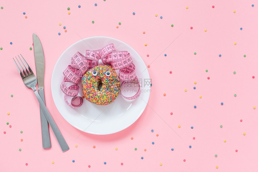碳水化合物从甜圈中提取的女人滑稽脸眼睛和头发从盘子上的厘米胶带粉红色背景的餐具饮食或不健康的物概念顶视图平躺复制空间从甜圈中提取图片