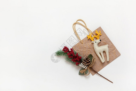 传统的项目快乐金黄色圣诞礼物袋白色的有黄角玩具鹿红莓和白背景针头的红色树枝复制空间节日新年销售购物概念平面观背景图片