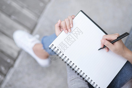 写作使用笔记本纸写字的顶端女手在公共园户外露天用笔记本打印空的上市图片