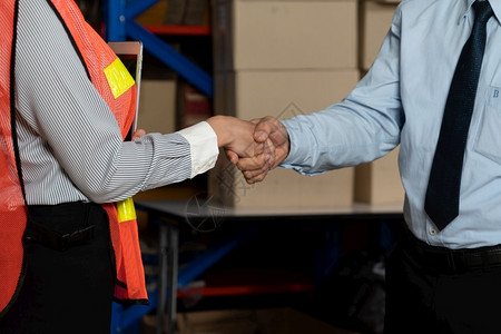 安全仓库工人与经理握手物流供应链和仓库业务概念工人与经理握手协议架子图片