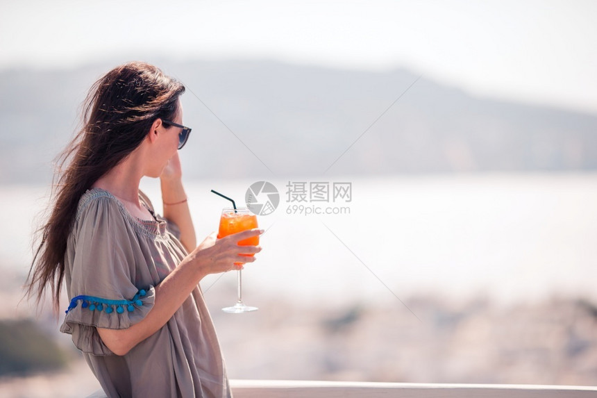 酒精米科诺斯在外咖啡厅的快乐女青年喝着美味饮料高加索旅游者享受欧洲节日令人惊叹的景象是古老城市和海边在室外咖啡厅的快乐女图片