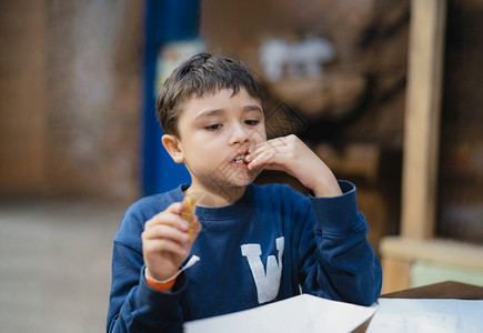 饥饿男孩在吃Churros棒学校儿童在咖啡厅午餐后吃零食健康儿童坐在咖啡店吃饭甜点请享用夏天幸福高清图片素材