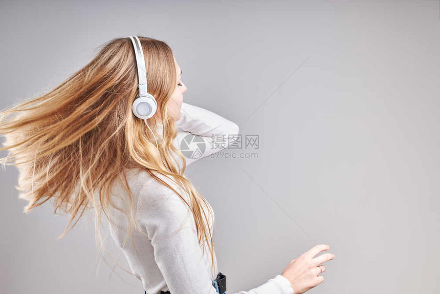 年轻女孩聆听音乐流内容于观看视频享受聊天与朋友使用智能耳机对面做手势表情的交谈坐在浅灰色背景上的耳机快乐有趣的溪流图片