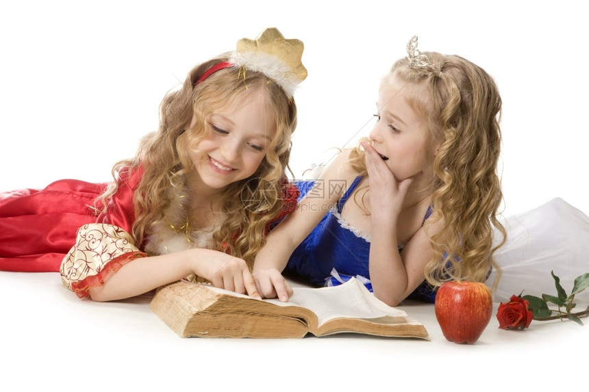 颜色仙女苹果两个美丽的小姑娘穿着公主服装的金发长头穿着公主服装在白色背景上读一本魔法书红色和蓝帝国礼服红和蓝色帝国礼服图片
