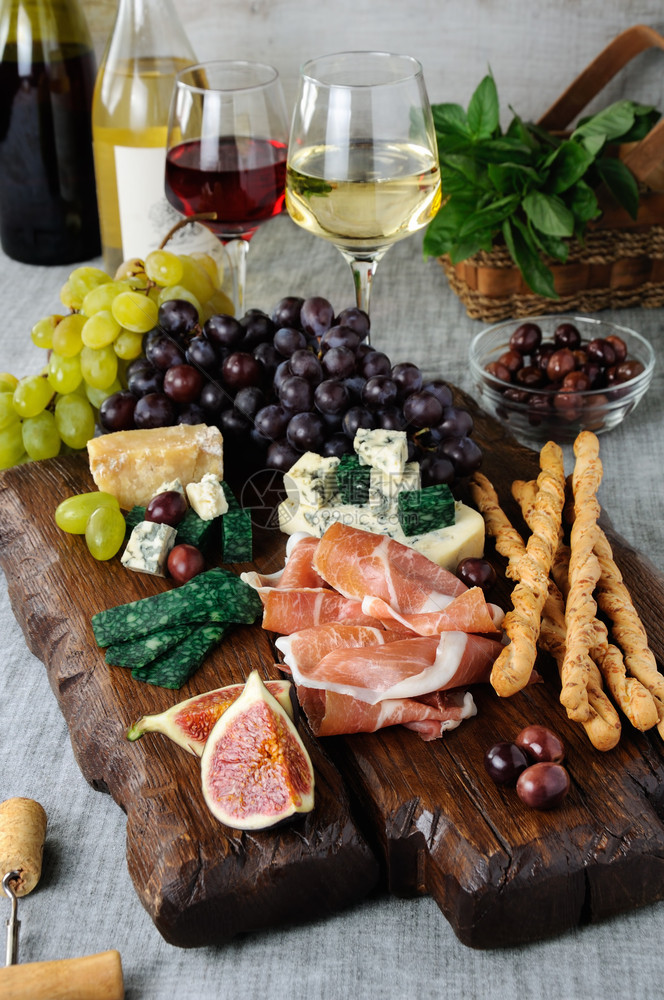 木板上的安提帕斯托Antipasto配有香菜不同种类的奶酪葡萄和无花果子菜肴小时自助餐图片