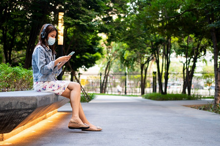 在公共场所使用智能手机佩戴防护口罩的女性图片