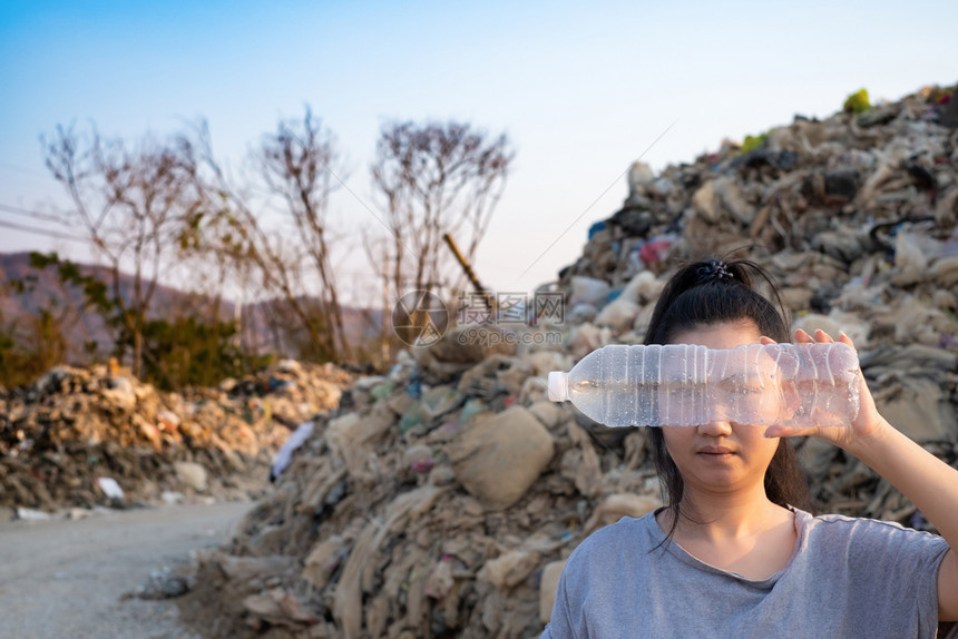 处理地球喝这些废物来自城市和工业地区无法除掉臭味和有毒残留物堆积如山的垃圾背景这些废物来自城市和工业地区妇女手持用一个清晰的塑料图片
