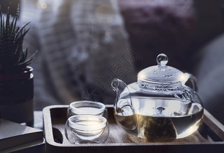 个子矮清爽净的茶壶和两杯个子在清晨光照亮的咖啡桌上餐盘装有轻蒸汽或可以作为下午茶水的可舒适场景用玻璃茶壶书包和锅炉加面粉优质的温暖背景