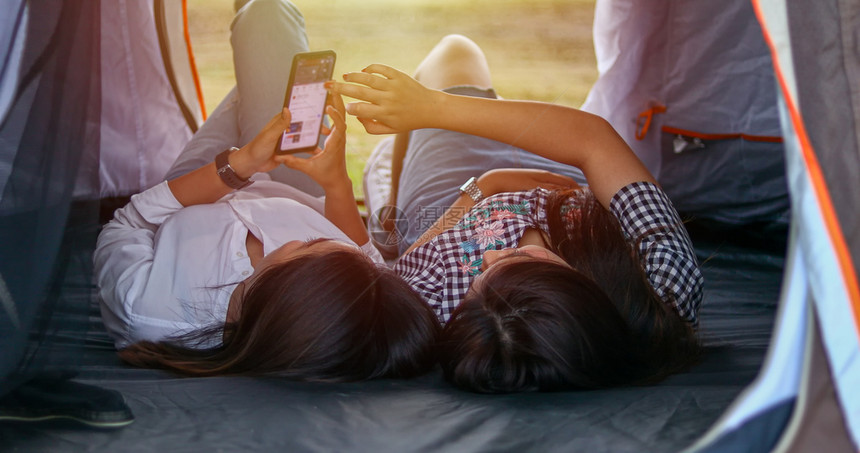 一群亚洲朋友玩UkeleleUkelele花时间在暑假野餐他们快乐并使用智能手机自拍放松假期概念旅行时间自然喝假期他们图片
