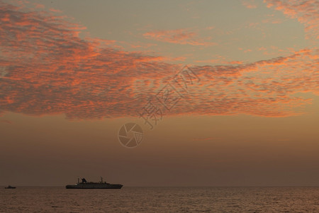 夜晚海洋一艘船在地平线上航行光辉多彩的日落天空平静低潮海滨环境图片