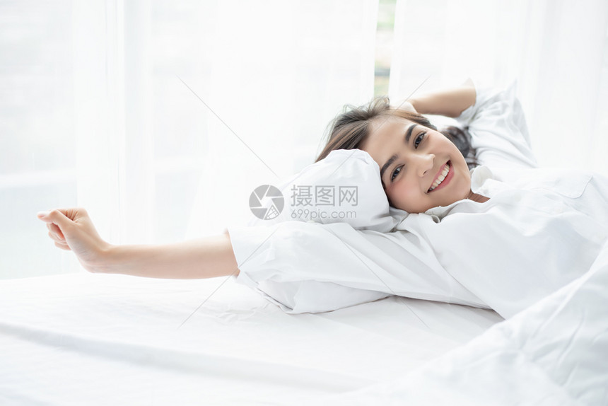 好的冥想亚洲女人美丽的年轻微笑女人坐在白床上睡觉早在卧室里舒展身体在床上醒来后充分休息自在图片