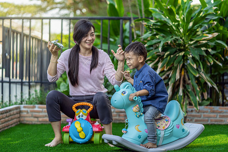 坐着亚洲单身母亲与儿子一起玩具吃饭住在现代学校的前沿草坪供自学或家庭校和单身母亲概念选择重点和有的重点生活在自己学习或家庭校和单孩子高清图片素材