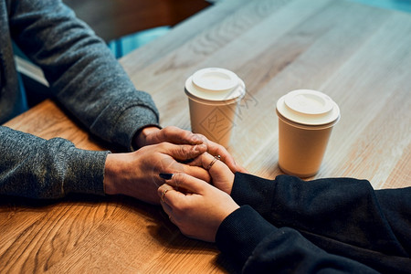 情侣牵手坐在咖啡馆里喝女人和男聊天休息在咖啡馆放松关心一种咖啡店图片