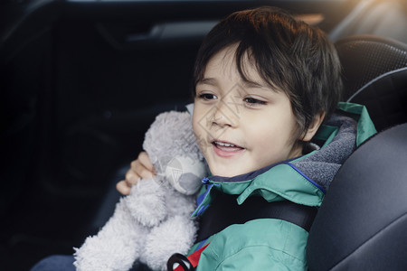 座位带着他的泰迪熊去探险男孩坐在汽车座椅上肩膀系着安全带手持软玩具望着车外看他正与学生一起旅行驾驶自在出去高清图片素材