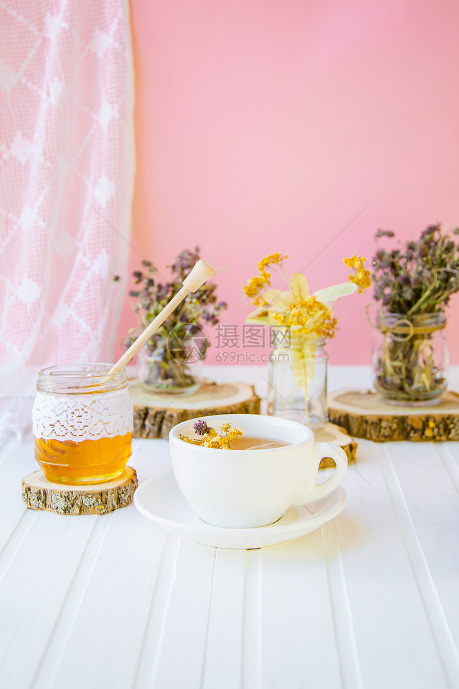 液体开花白茶杯用天然有机草药和一罐蜂蜜在白木桌上增加免疫力在寒冷的季节白茶杯用天然有机草药和一罐蜂蜜在白木桌子上增加免疫力户外图片