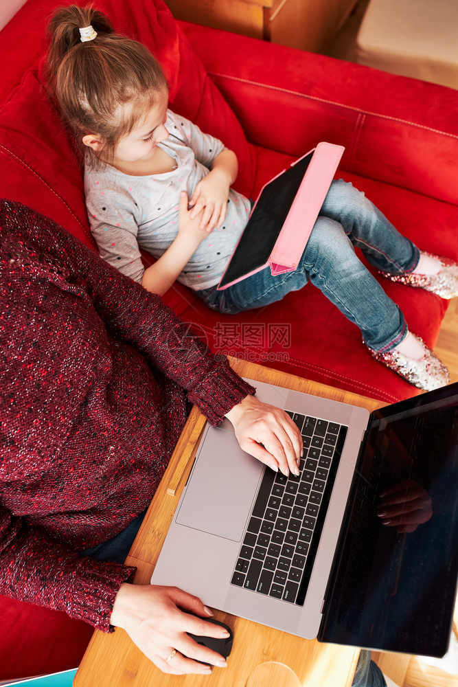 偏僻的家庭在CCOVID19隔离期间在家中笔记本电脑网上研讨会用笔记本电脑进行视频聊天呼叫流在线课程而她的女儿则在电脑面前看屏幕图片