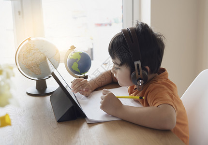 学龄前儿童使用平板电脑做功课的肖像通过在互联网上使用数字平板搜索信息家庭学校教育概念来从事功课的儿童Soft焦点写作读玩背景图片