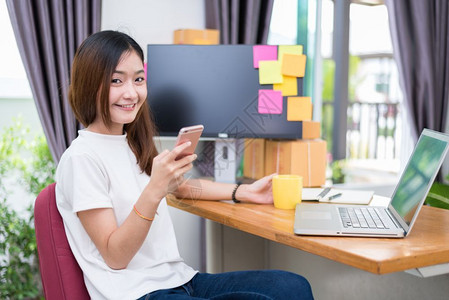 苦与乐正在做技术职的亚裔女办公室商业和市场营销中使用笔记本电脑及话以兼职概念在线购物与商业成功主题时享受生活工作愉快的心情乐工作背景