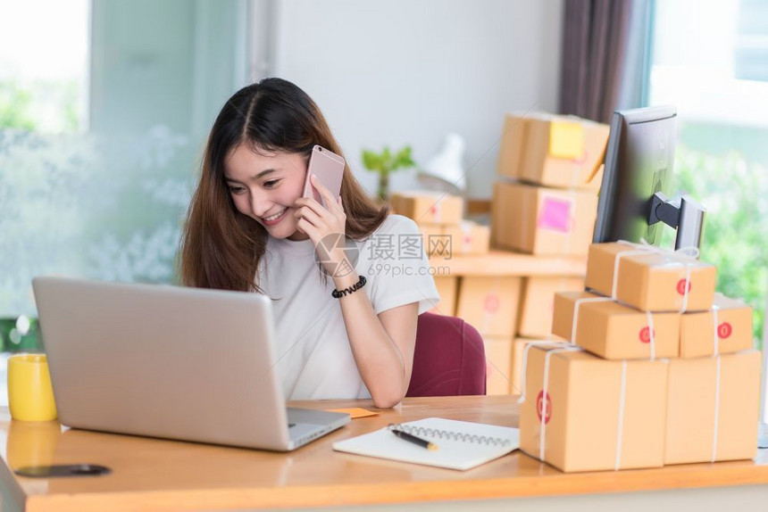 时间亚裔女在办公室商业和市场营销中使用笔记本电脑及话以兼职概念在线购物与商业成功主题时享受生活工作愉快的心情乐工作请享用尽管图片